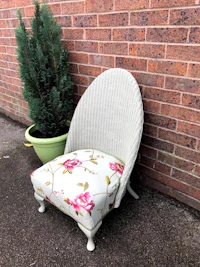 a wicker chair with a floral cushion in front of a brick wall