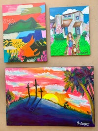 three paintings on a table with a house in the background