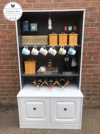 a white hutch with coffee cups and mugs on it
