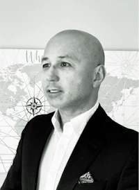 a bald man in a suit standing in front of a map