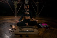 a woman meditating on a wooden floor at night