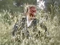 a man in a field with a mask on his face