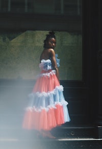 a woman in a blue and pink tulle dress standing on the steps of a building