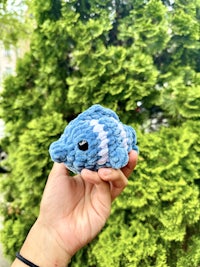 a person holding a crocheted blue fish toy
