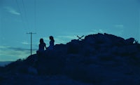 two people standing on top of rocks at dusk