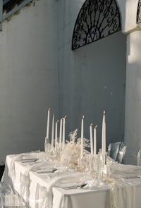 a white table setting with candles and white linens