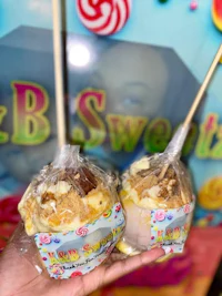 a person holding two lollipops in front of a candy store