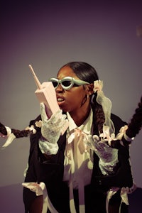 a woman holding a cell phone while holding a spider