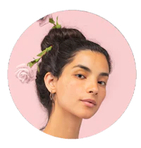 a woman with flowers in her hair on a pink background