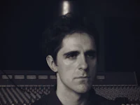 a black and white photo of a man in front of a mixing board