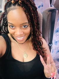 a woman wearing a black top with dreadlocks posing for a photo