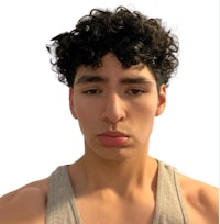a young man with curly hair looking at the camera