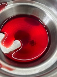 a close up of a red liquid in a metal bowl