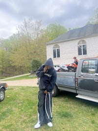 a man in a hoodie standing in front of a truck