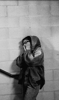 a black and white photo of a person leaning against a wall