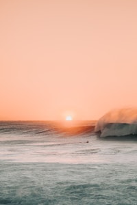a surfer is riding a wave at sunset