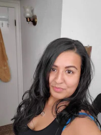 a woman in a black tank top is taking a selfie