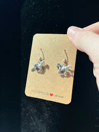 a person holding a pair of horse earrings on a card