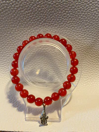 a bracelet with red beads on a white surface