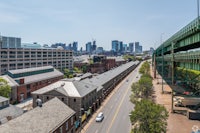 an aerial view of a city street with a bridge in the background