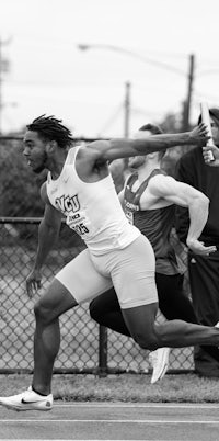 a black and white photo of a man running on a track