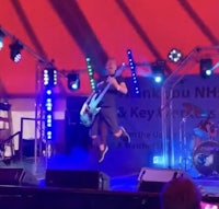 a man jumping in the air on stage at a concert