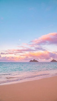 a beach with a pink sky and ocean in the background