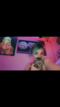 a girl is holding a cat in front of a purple wall