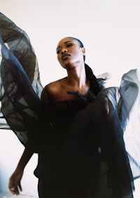 a woman in a black dress with her arms outstretched