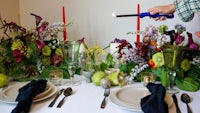 a man lighting a candle on a table full of flowers