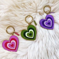 three heart shaped keychains on a furry surface