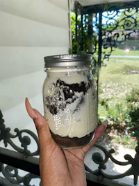 a person holding a mason jar with a cake in it