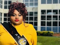 a woman in a yellow sash standing in front of a building