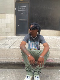 a man with dreadlocks sitting on the steps of a building