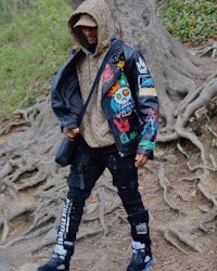 a man wearing a hoodie and jeans walking through a wooded area
