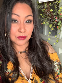a woman in a yellow floral top posing for a photo