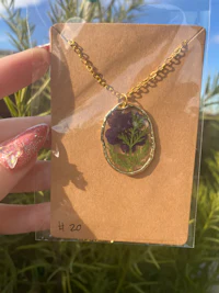 a person holding a necklace with a flower on it