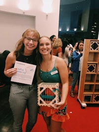 two women posing for a photo with a wooden box