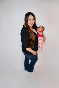 a woman holding a baby in front of a white background