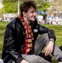 a man sitting on the grass with a scarf on his head