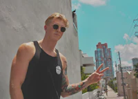 a man wearing a black tank top with tattoos and a peace sign