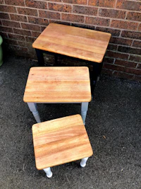 three wooden tables sitting on a brick wall