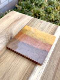 a wooden coaster with a yellow, orange, and brown stripe