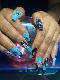 a woman with blue and black nails holding a blue crystal