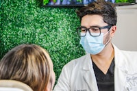 a dentist is talking to a patient wearing a mask