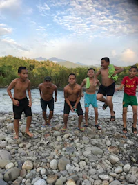 a group of boys standing on rocks near a river