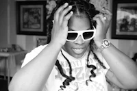 a black and white photo of a woman with dreadlocks and sunglasses
