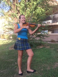 a girl in a kilt playing a violin
