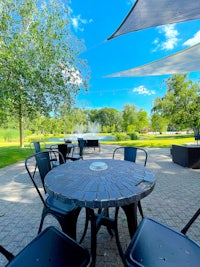 a table with chairs and umbrella in a park