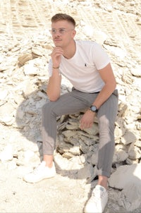 a young man sitting on a pile of rocks
